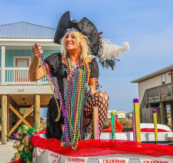 Lady posing in Fort Morgan parade with hands full of beads.